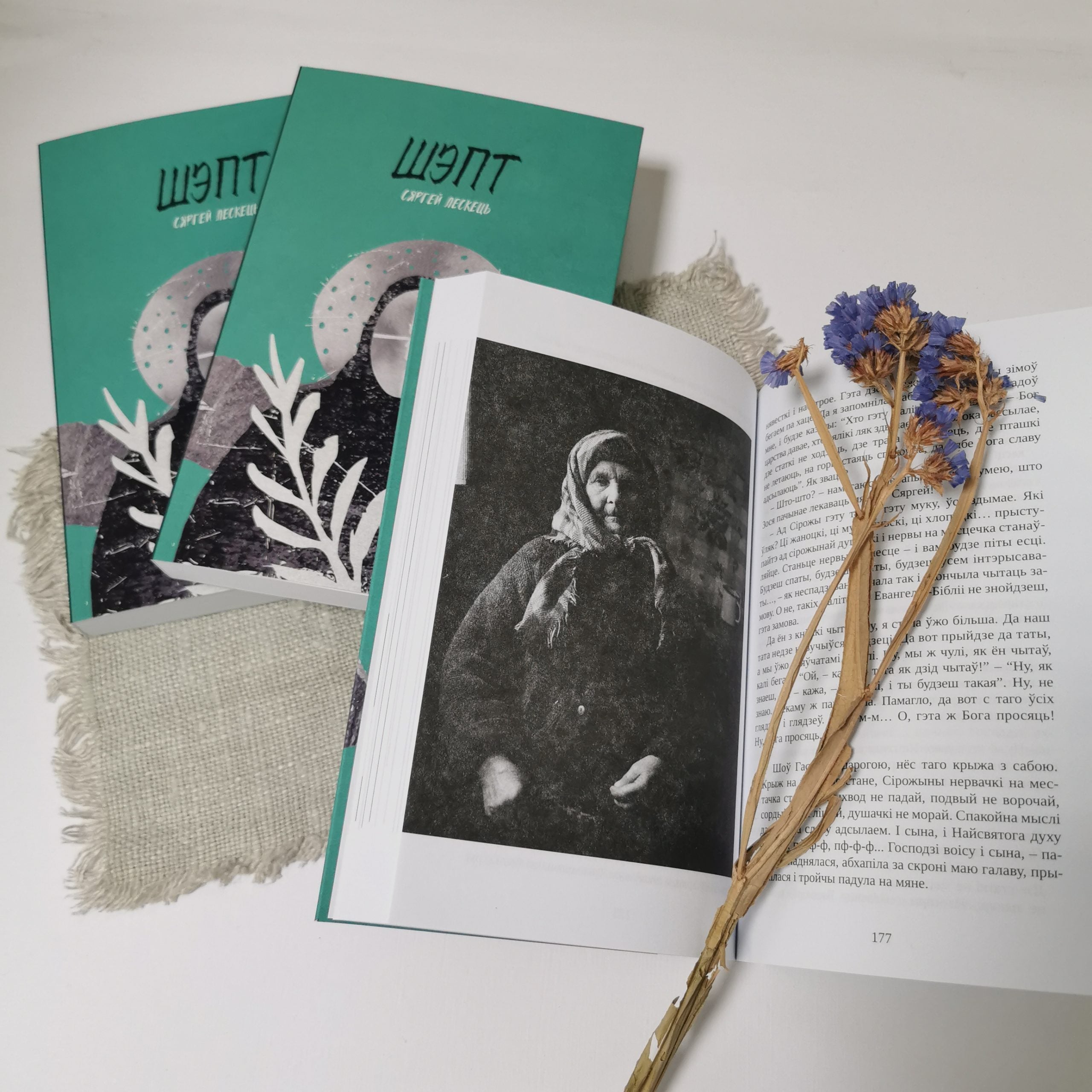 Book Whisper Siarhiej Leskieć covers shown with dried flowers and an open page showcasing Belarusian rural magic.