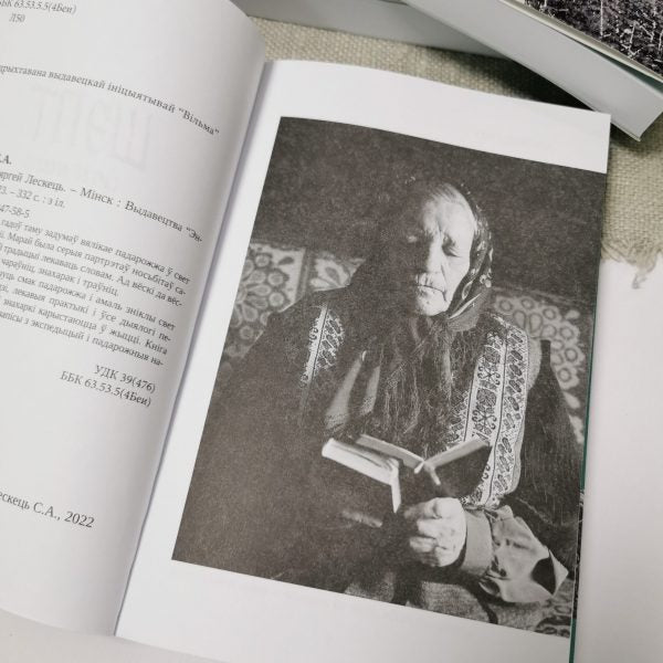 Book Whisper Siarhiej Leskieć showing a woman in traditional clothing reading, capturing the essence of Belarusian rural magic.